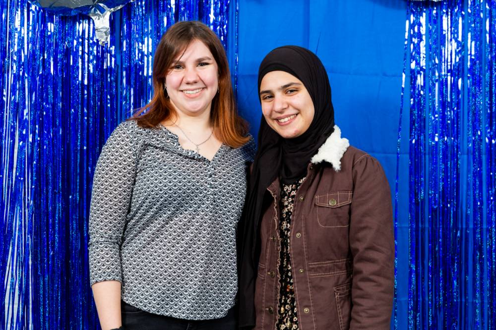 Student and advisor pose in front of backdrop